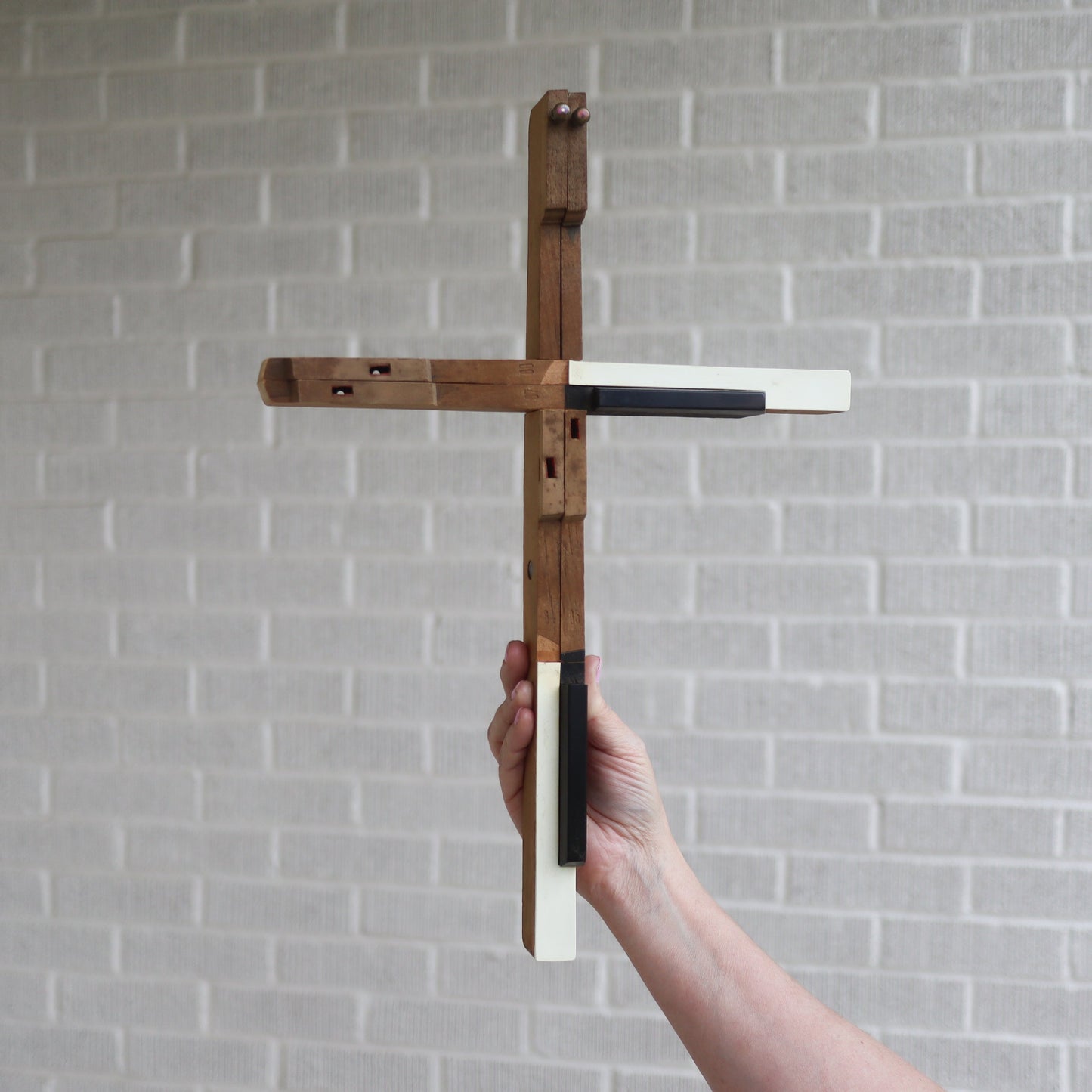 Wooden piano key cross by Dennehey Design Co. featuring detailed craftsmanship and natural wood finish.