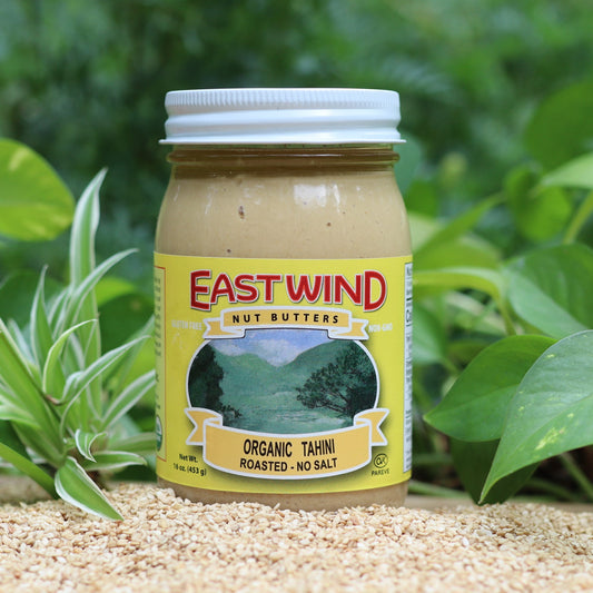 Organic Tahini from East Wind Crafts in a jar, showcasing its smooth, creamy texture and light beige color.