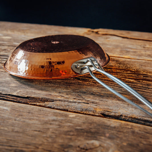 Close-up of a Sertodo copper skillet handle showing the detailed craftsmanship and polished copper surface.