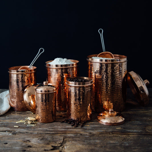 Set of Sertodo copper kitchen canisters in various sizes, featuring sleek cylindrical design and hammered finish for storage.