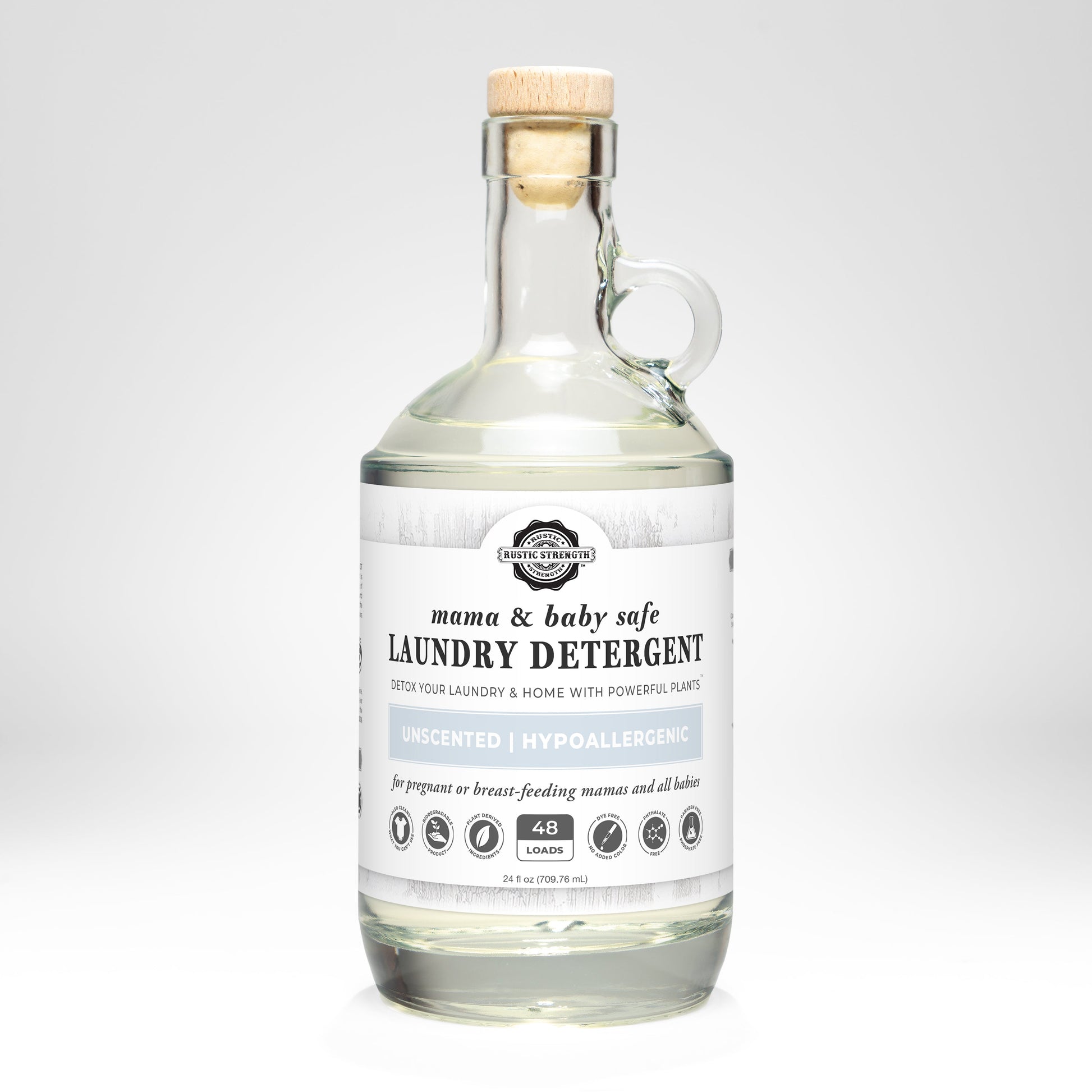 A clear glass bottle with handle contains Rustic Strength Laundry Detergent | Mama + Baby Safe for sensitive skin, unscented, 48 loads, shown against a plain white background.