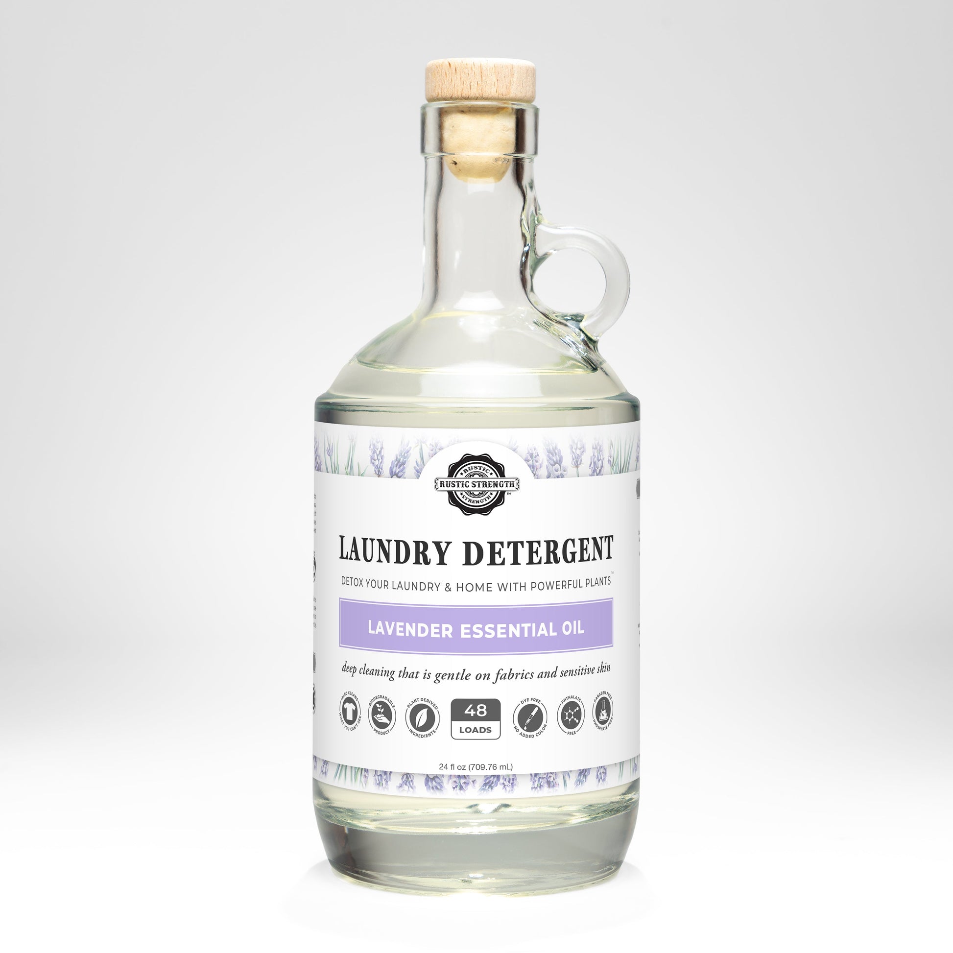 A clear glass bottle with a cork lid contains Rustic Strength’s Laundry Detergent | Lavender. The label highlights its hypoallergenic formula and gentle touch, adorned with lavender illustrations.
