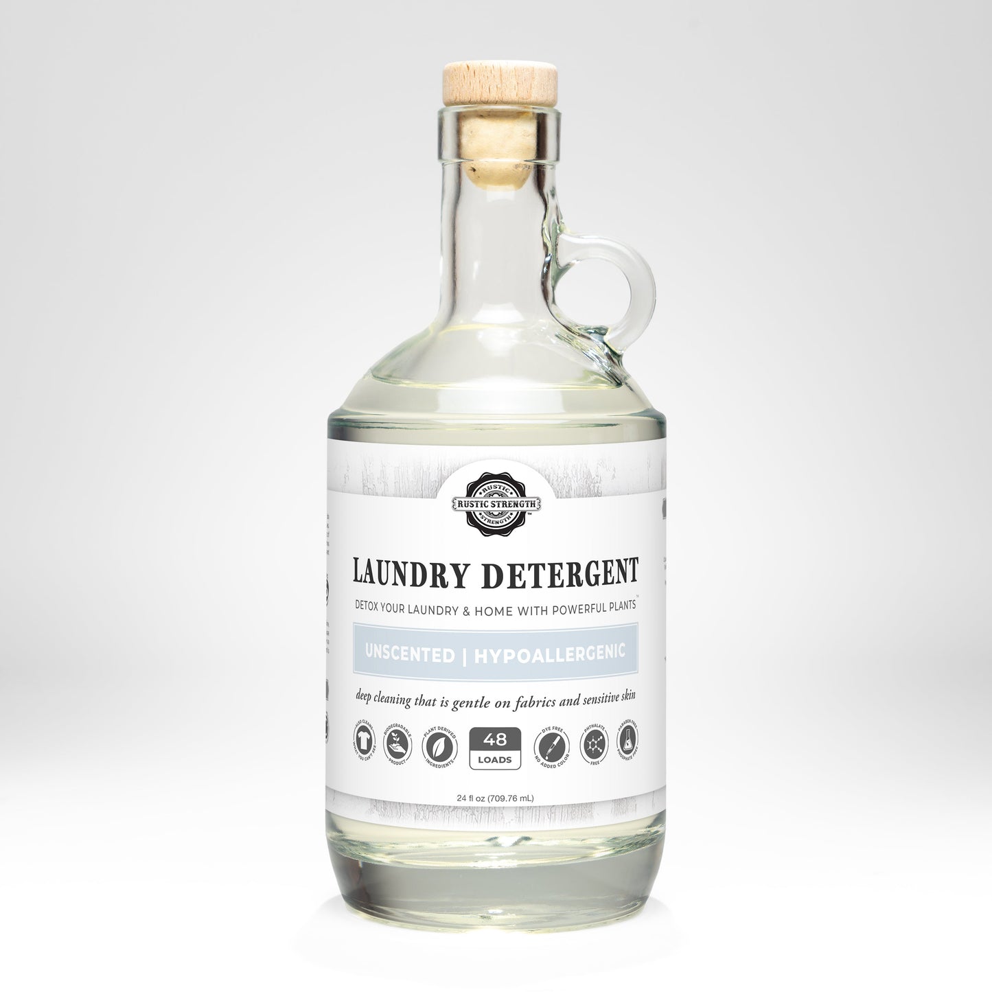 Rustic Strengths Laundry Detergent | Unscented comes in a clear glass bottle with a cork lid. The white label notes 48 loads, plant-powered, hypoallergenic ingredients, and that this biodegradable formula is gentle on fabrics.