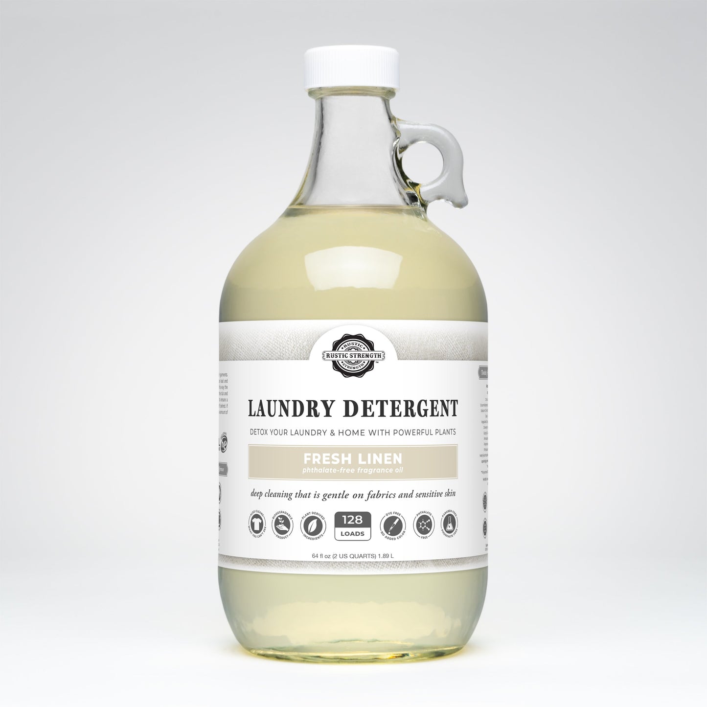 A clear glass bottle of Rustic Strength Laundry Detergent | Fresh Linen, with a handle and white label, offers 128 loads of biodegradable, hypoallergenic detergent that’s gentle on fabrics and safe for sensitive skin.