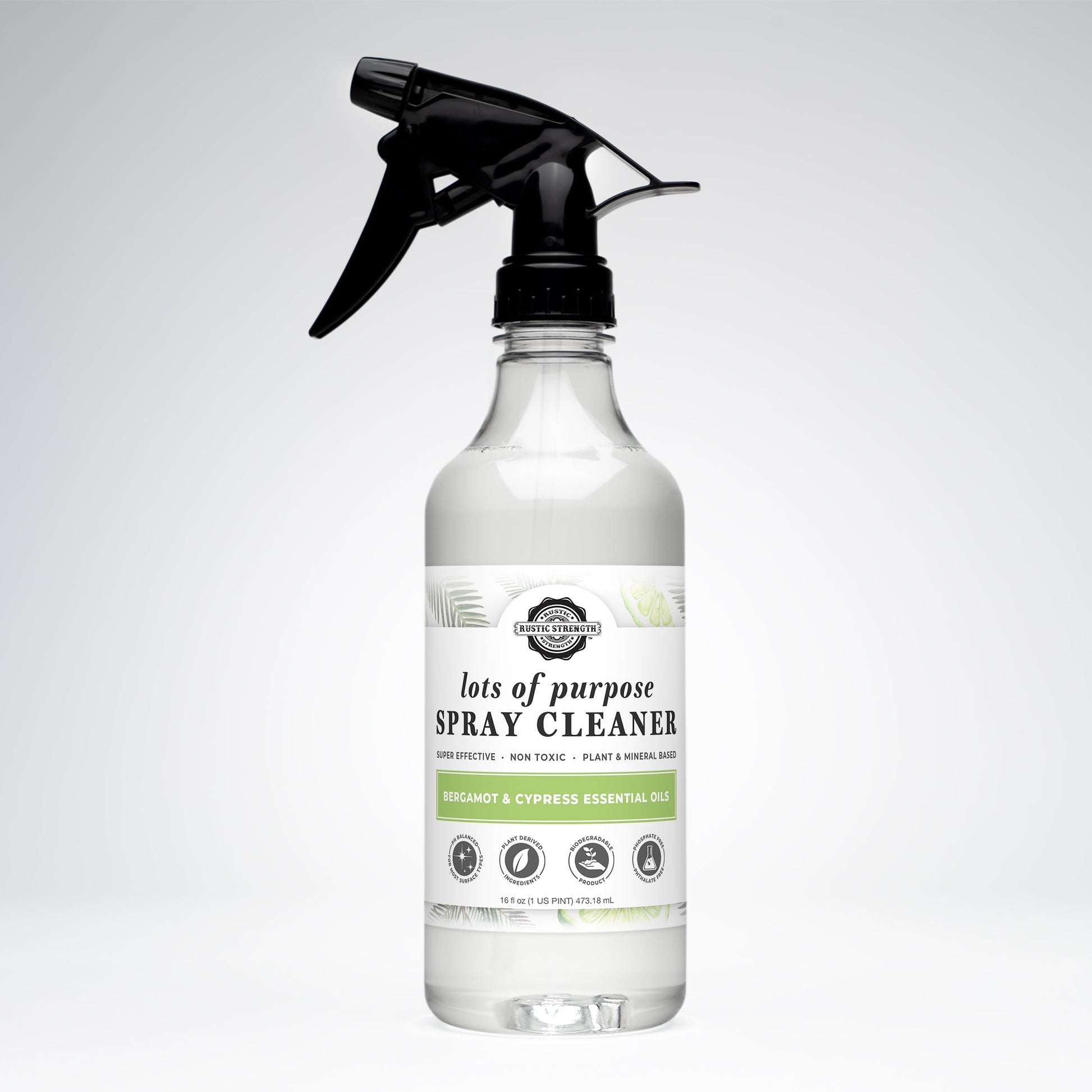 A clear spray bottle labeled Rustic Strength Lots of Purpose Spray Cleaner | Bergamot & Cypress has a black trigger nozzle with green accents and icons showcasing its plant-based, non-toxic multi-surface formula, set against a white background.