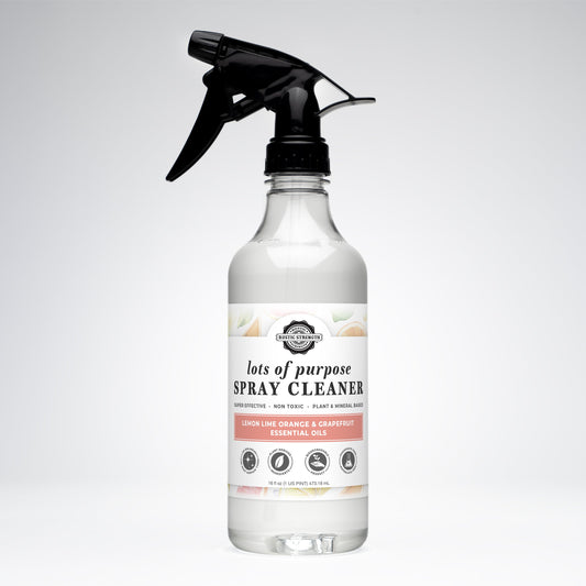 A clear Rustic Strength Lots of Purpose Spray Cleaner with lemon, lime, orange, and grapefruit oils is shown with a black spray nozzle against a white background.