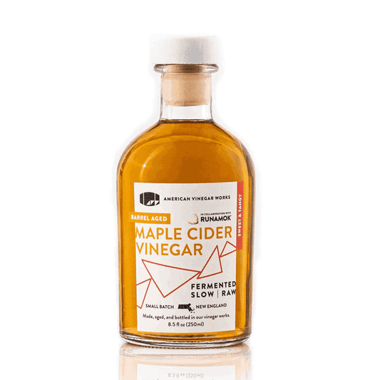 Front view of American Vinegar Works Maple Cider Vinegar bottle with a label featuring a maple leaf and collaboration branding.