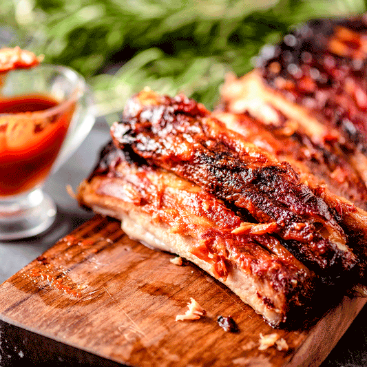 Pig of the Month BBQ Peach Sriracha Baby Back Ribs showcasing glazed, flavorful pork ribs with a spicy peach sriracha sauce.