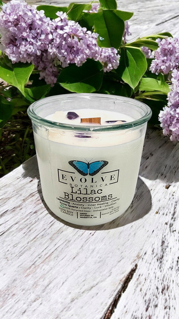 Evolve Botanica Rocks Candle Lilac Blossoms with wood wick and Lepidolite gemstone, soy wax in a glass container.