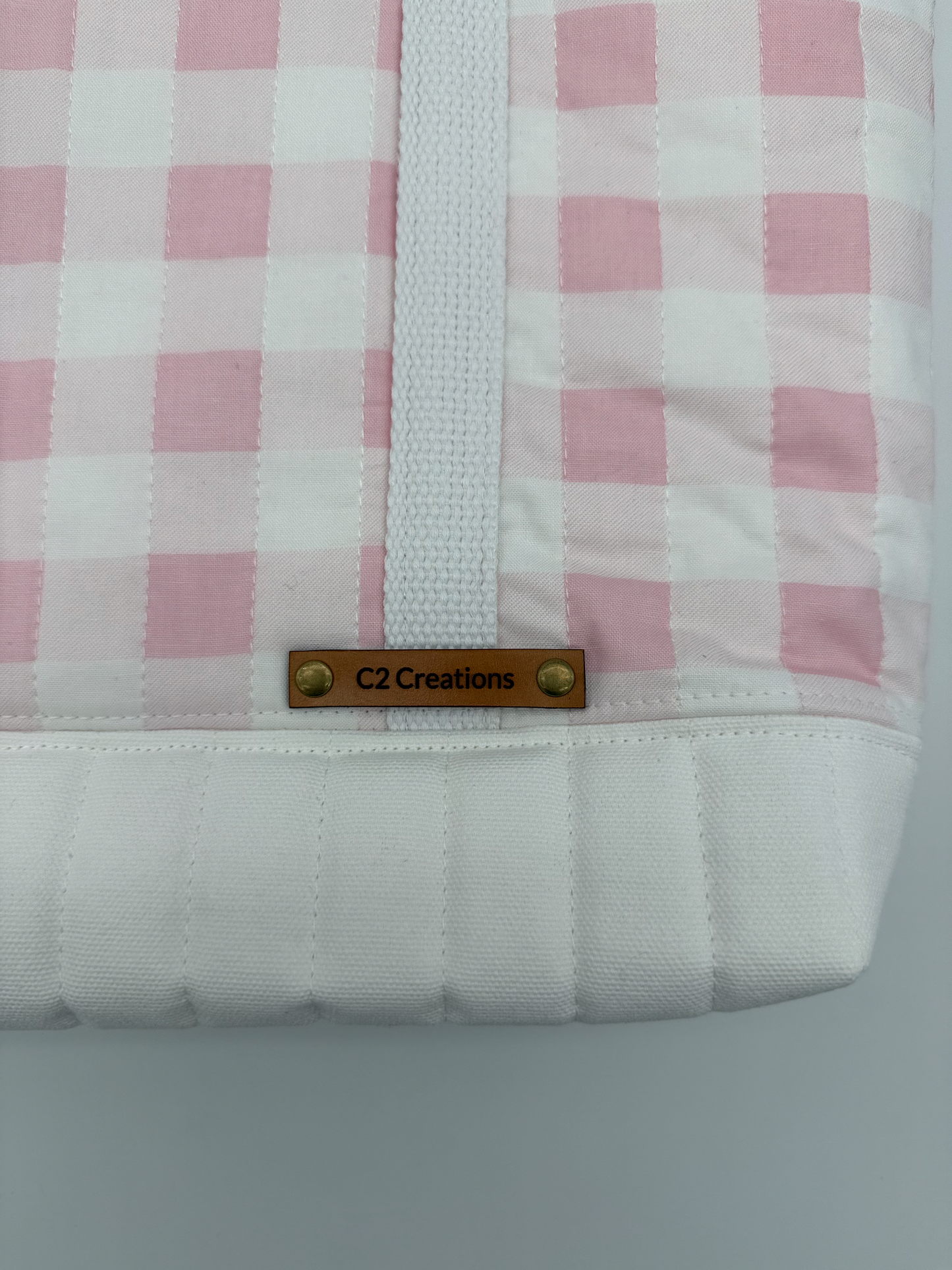 Close-up of a pink gingham quilted tote bag with snap closure, handmade canvas design by C2 Creations LLC.