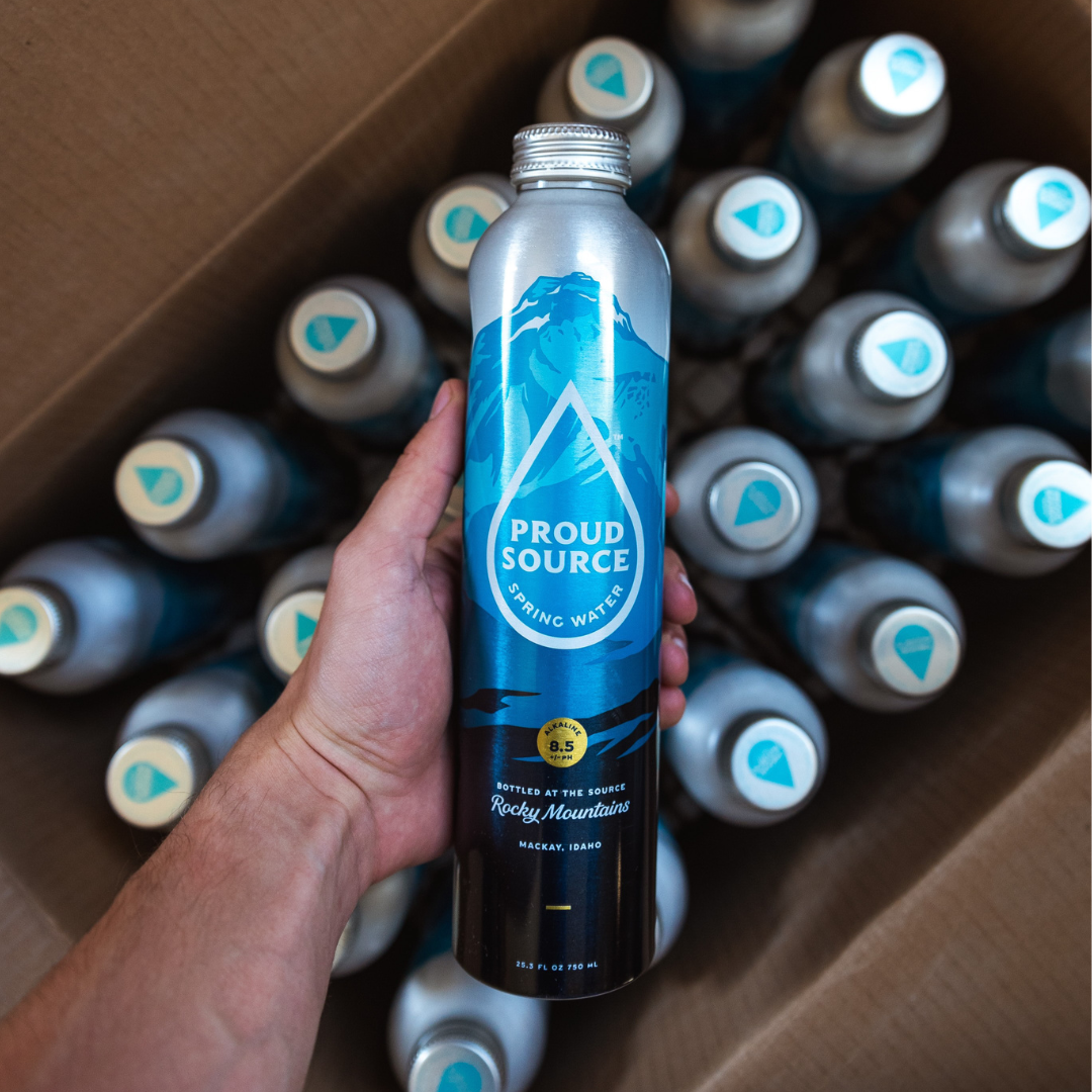 Clear bottle of PROUD SOURCE WATER alkaline spring water with natural mineral content, standing upright with a clean label.