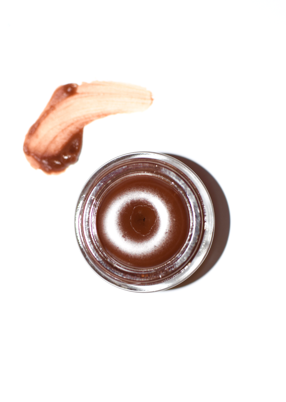 Close-up of plant makeup Cocoa Lip Gloss tube showing the product's packaging and applicator.