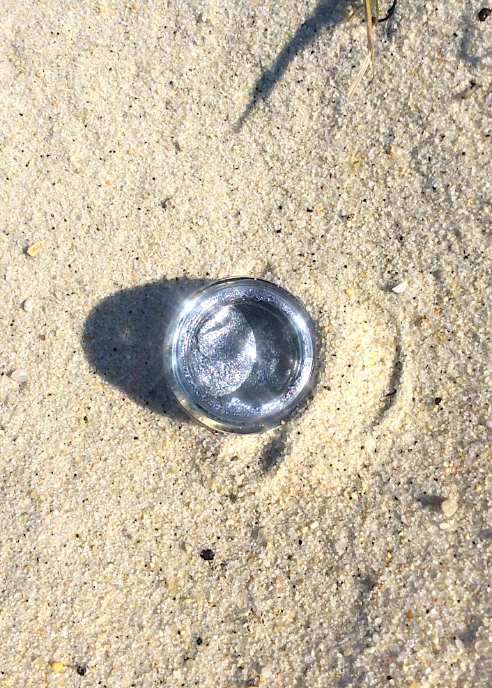 Space Goth Gloss by plant makeup with a dark, shimmering purple finish, shown in a close-up of the lip gloss applicator.
