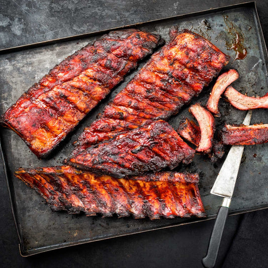 Smoked baby back ribs from Pig of the Month BBQ, part of a 3-rib sampler pack, ready for grilling or serving.