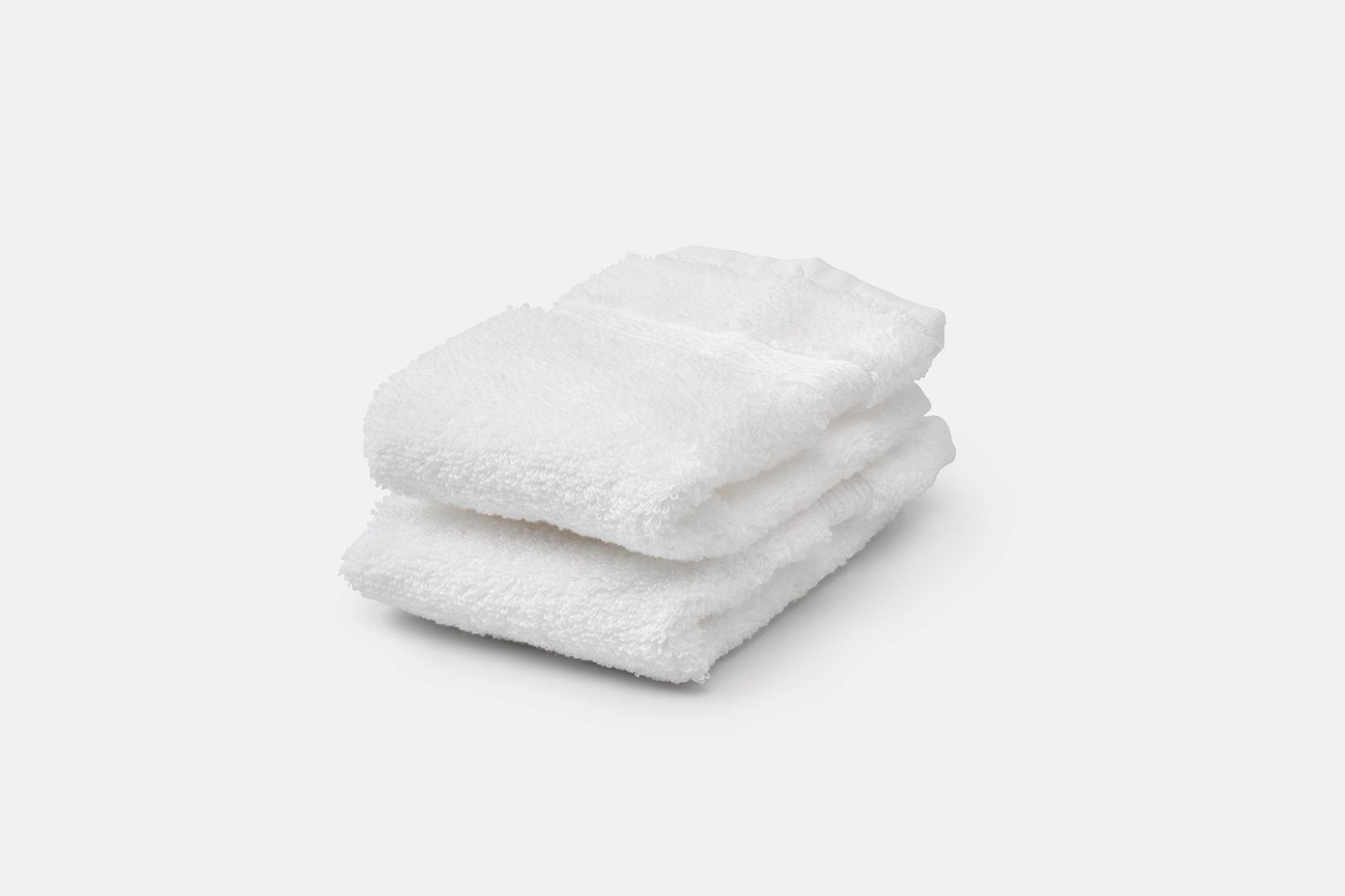 Stack of white luxury USA cotton bath washcloths by American Blossom Linens, soft and natural for bathroom use.
