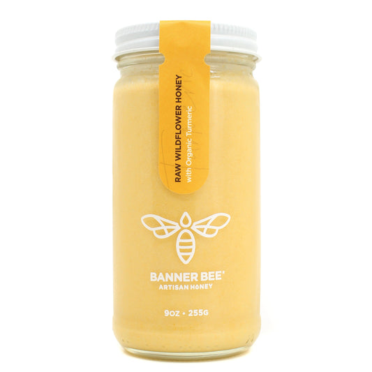 Jar of turmeric enriched raw honey from BannerBee Company LLC, showing golden honey infused with turmeric roots.