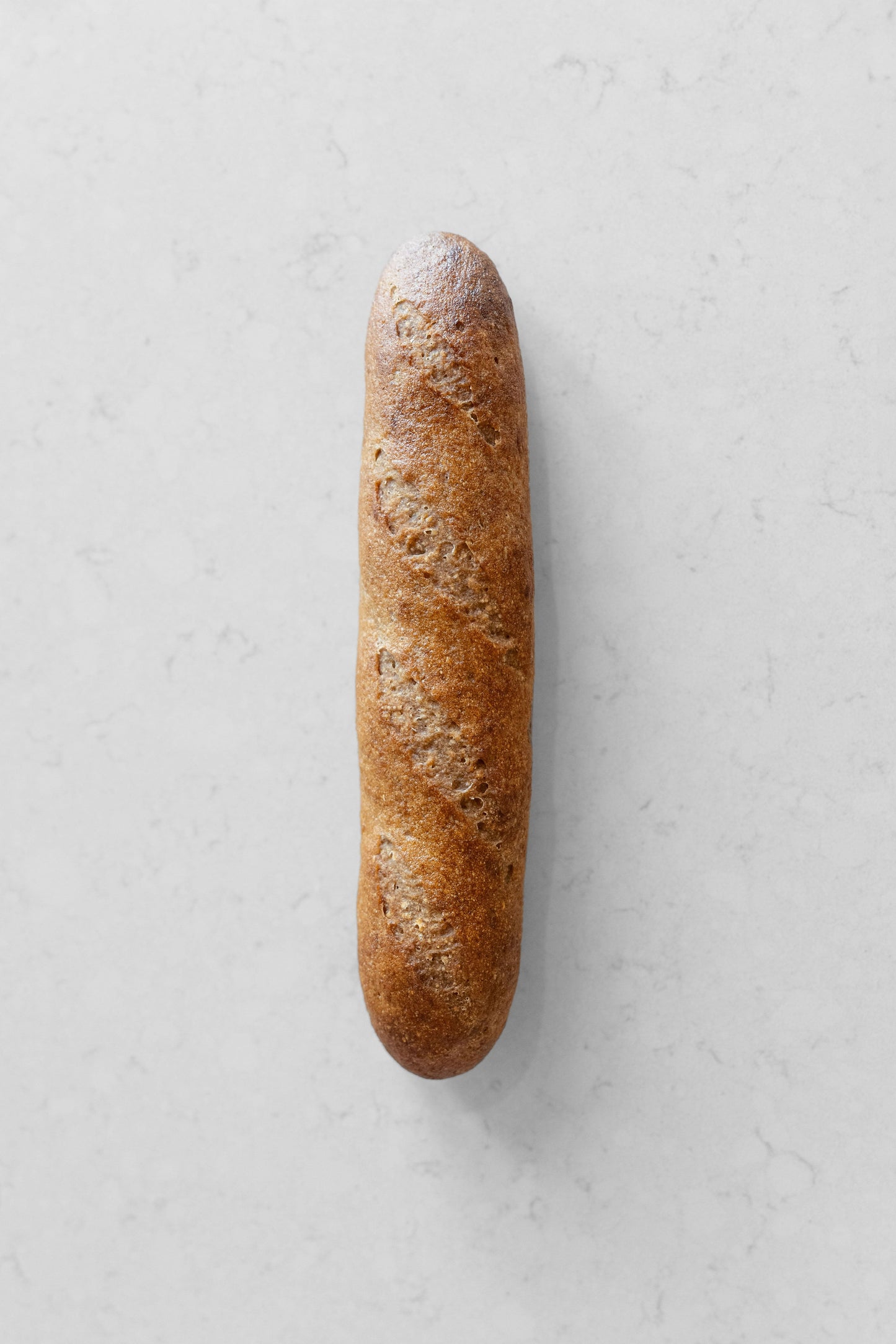 Fresh gluten-free vegan sourdough baguette from Heaven Gluten Free Bakery, showcasing its crusty golden exterior and rustic shape.
