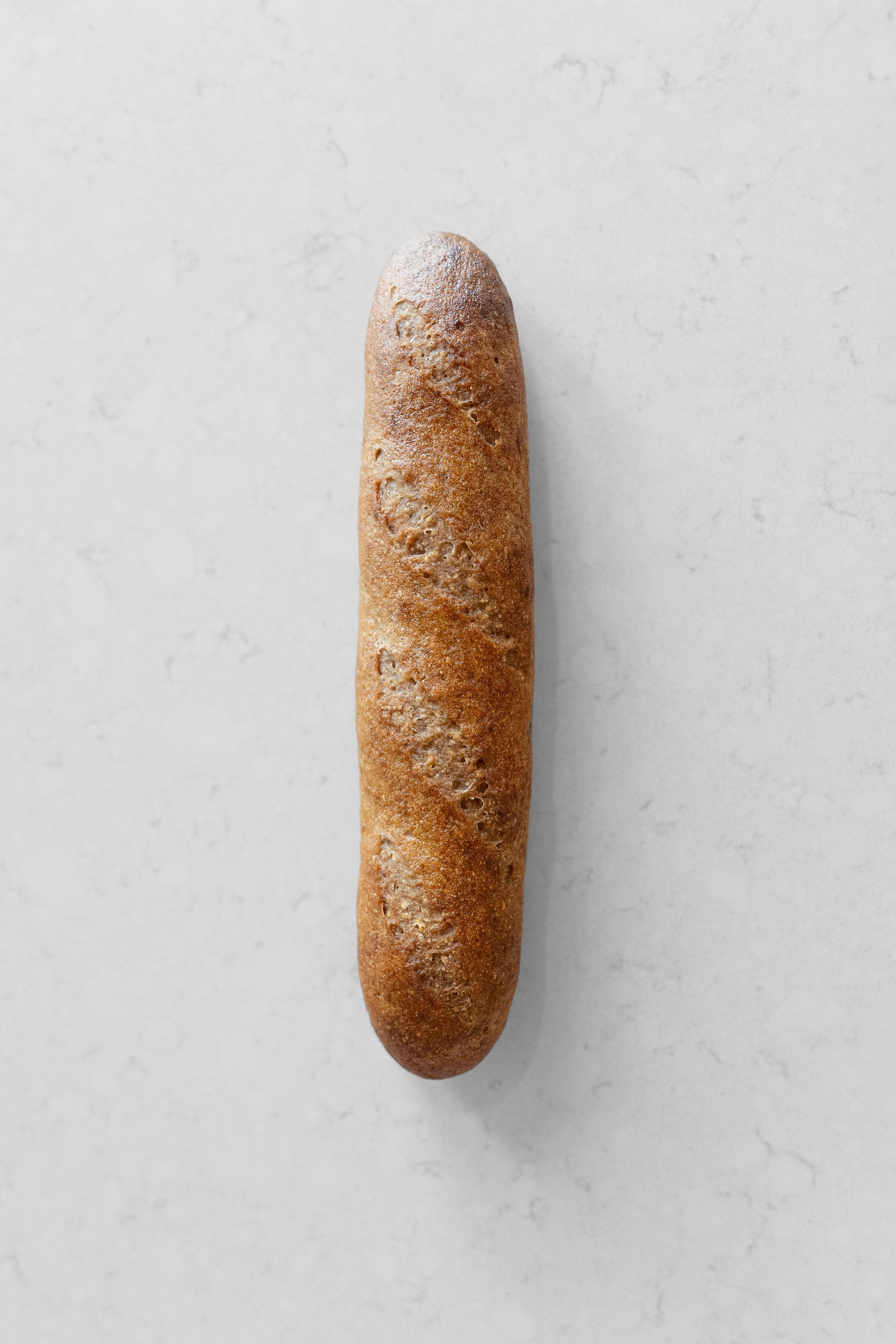 Fresh gluten-free vegan sourdough baguette from Heaven Gluten Free Bakery, showcasing its crusty golden exterior and rustic shape.