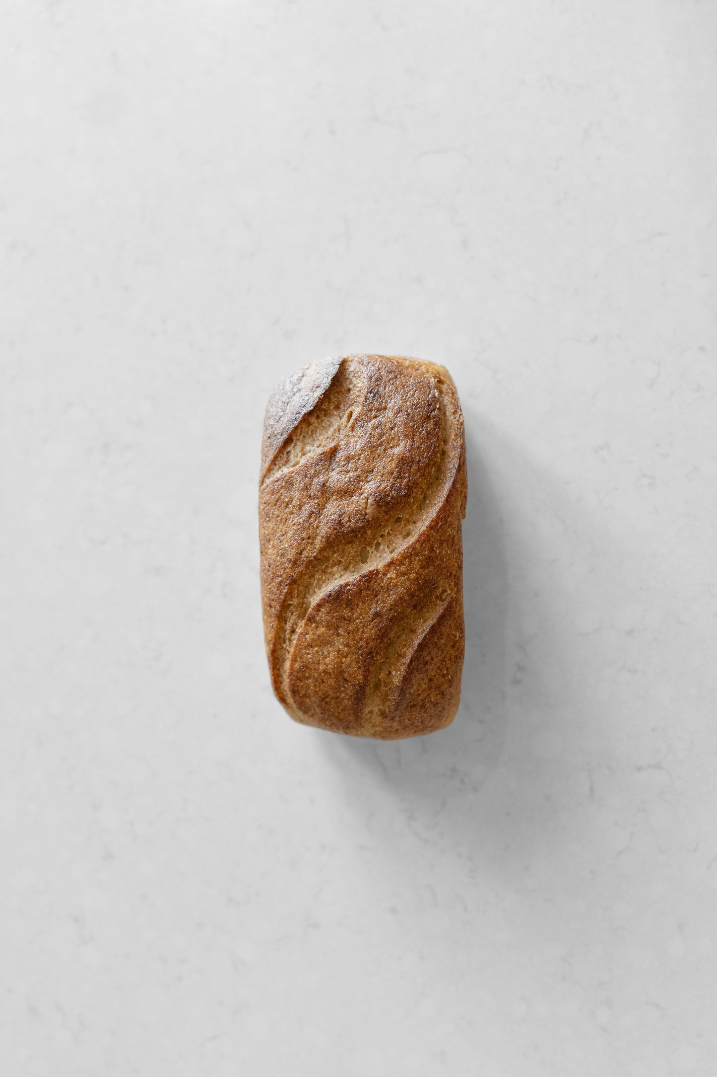 Sourdough loaf by Heaven Gluten Free Bakery, white, gluten-free, vegan sourdough bread on a cutting board.