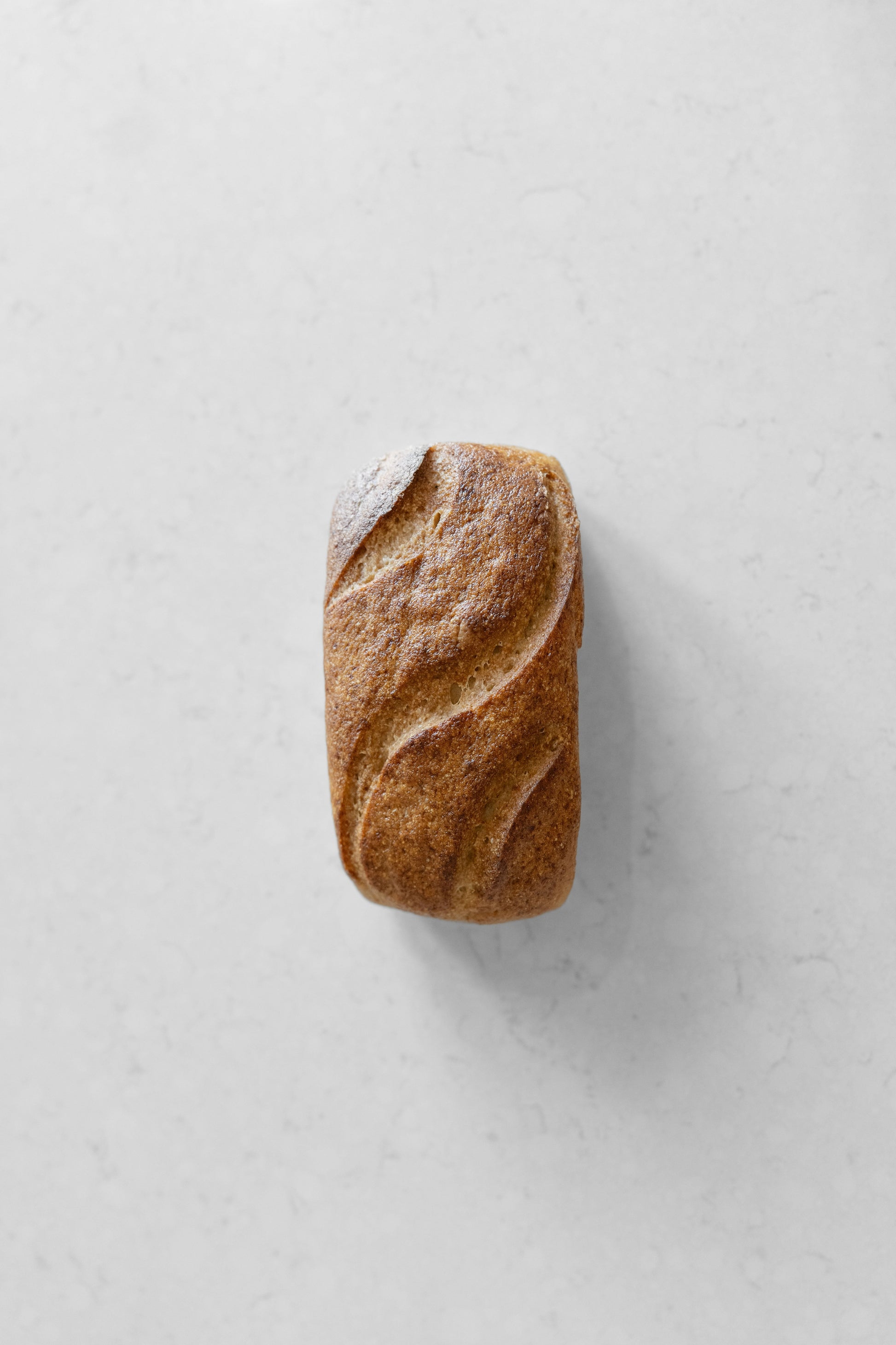 Sourdough loaf by Heaven Gluten Free Bakery, white, gluten-free, vegan sourdough bread on a cutting board.