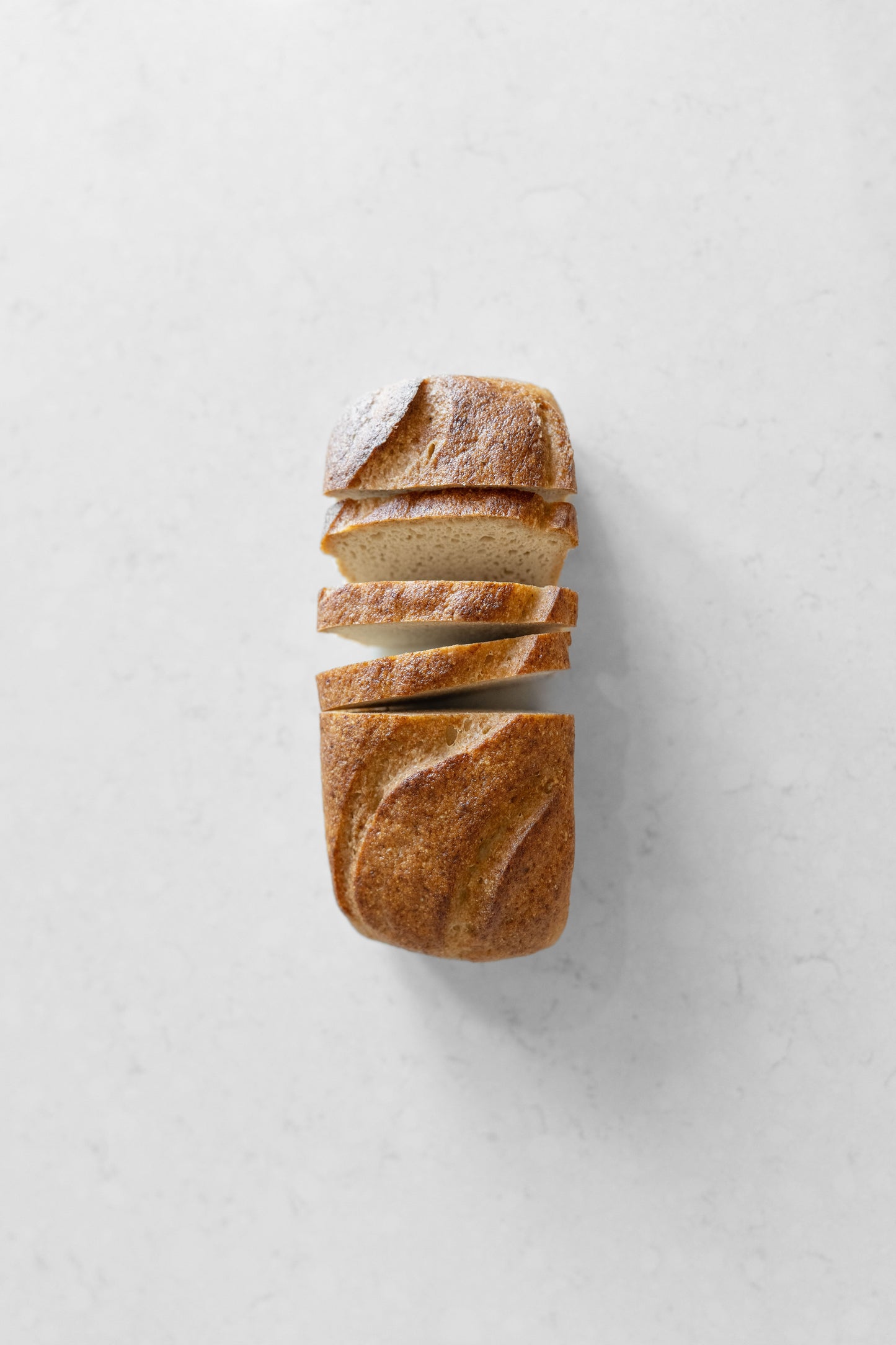 Heaven Gluten Free Bakery white sourdough vegan loaf with gluten-free ingredients, sliced and placed on a wooden board.