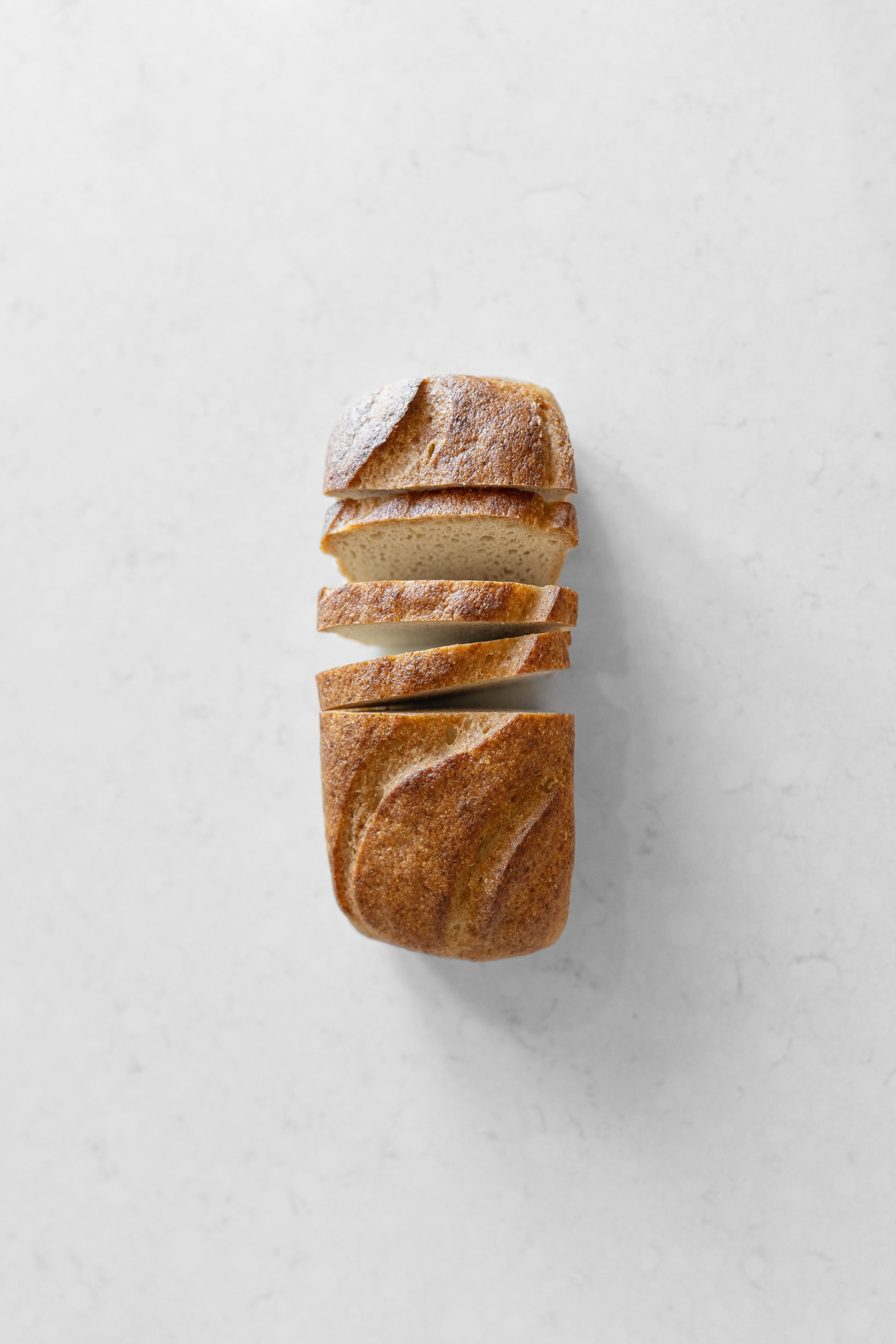 Heaven Gluten Free Bakery white sourdough vegan loaf with gluten-free ingredients, sliced and placed on a wooden board.
