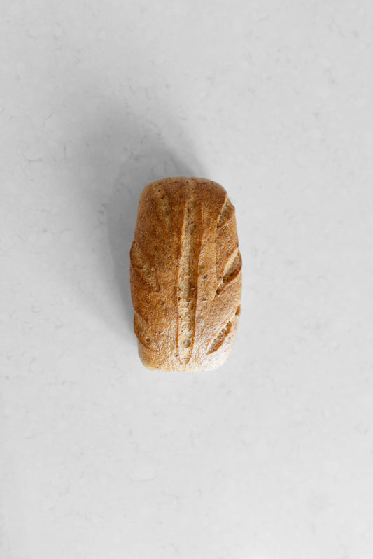Sourdough loaf from Heaven Gluten Free Bakery, gluten-free and vegan Caraway Sourdough bread on a wooden surface.