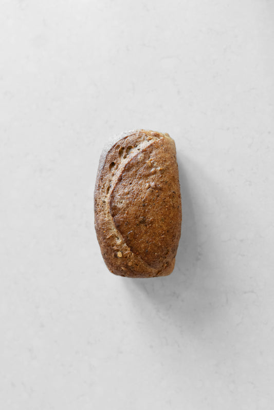 Gluten-free vegan sourdough loaf with mixed seeds from Heaven Gluten Free Bakery, sliced to show seed-filled interior.