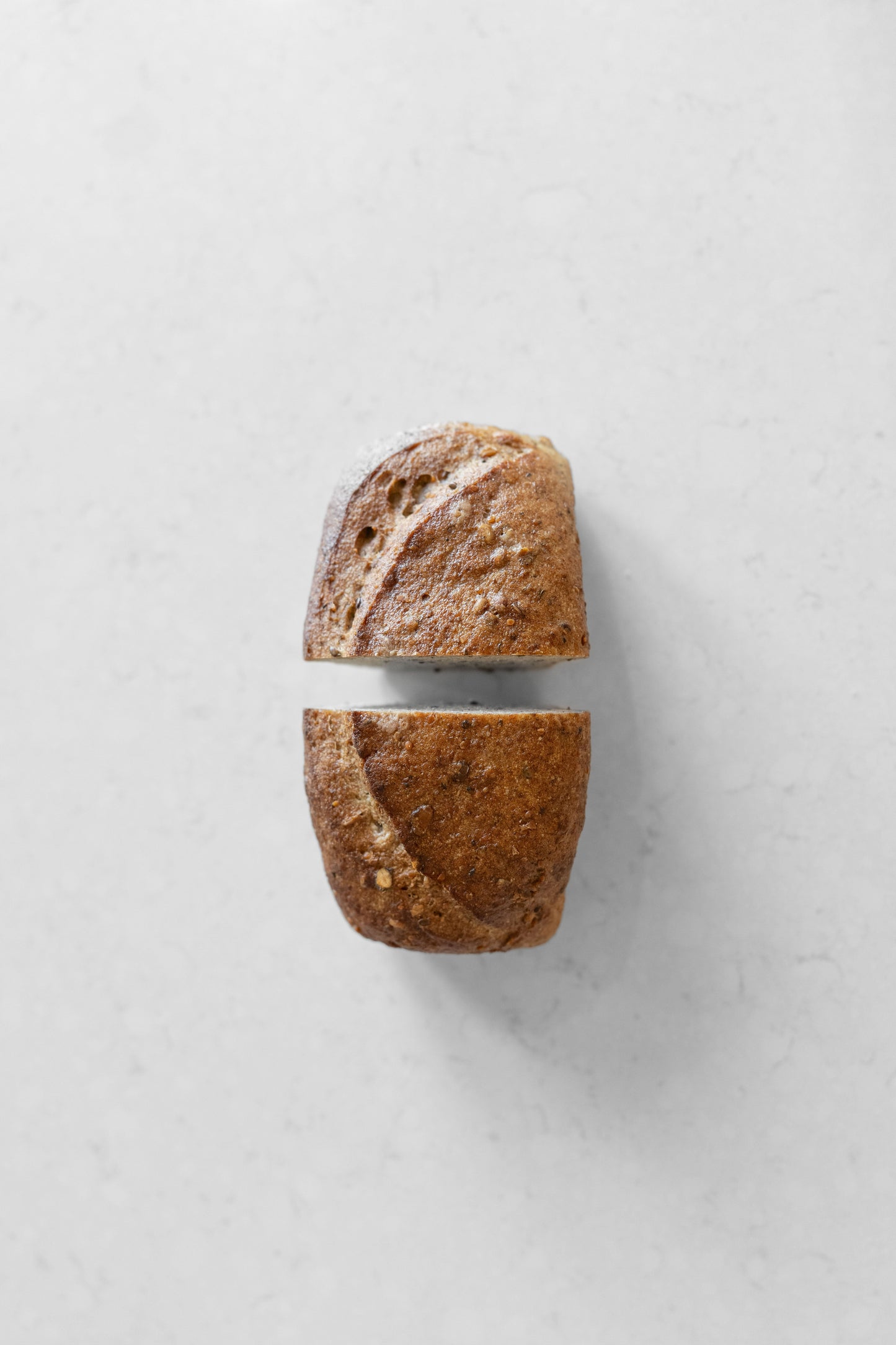Gluten-free vegan sourdough loaf with mixed seeds from Heaven Gluten Free Bakery, shown sliced with visible seeds inside.