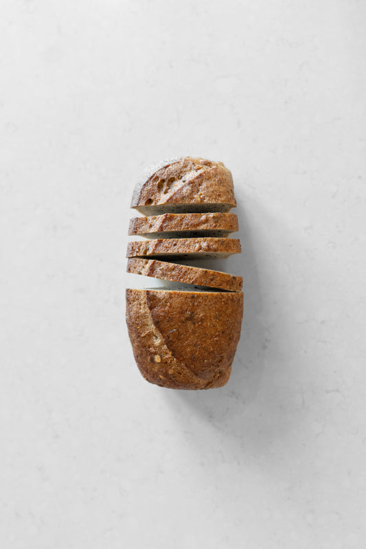 Gluten-free vegan sourdough loaf with assorted seeds from Heaven Gluten Free Bakery, sliced to show its dense texture and seed topping.