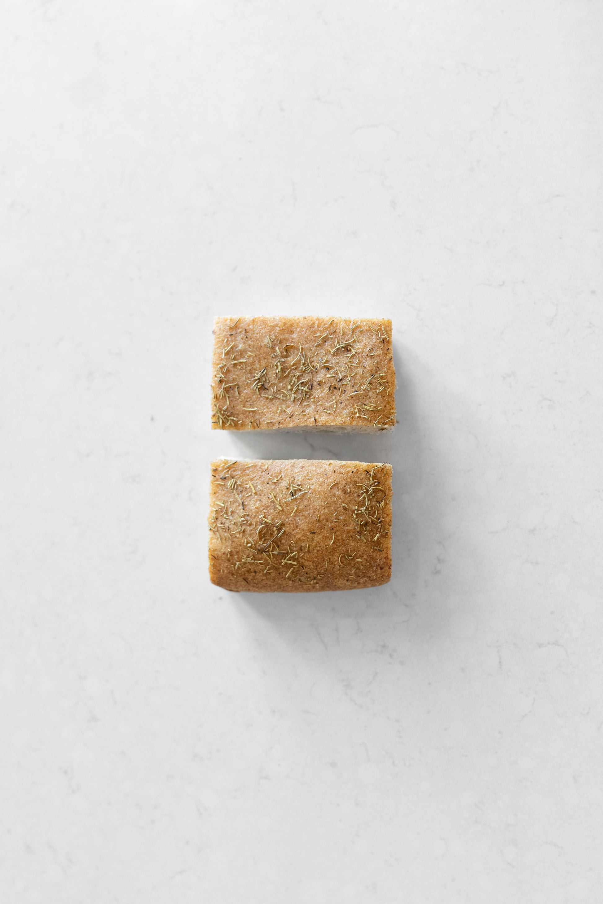 Two slices of gluten-free rosemary focaccia sourdough bread from Heaven Gluten Free Bakery, showing the topped, aromatic bread slices.