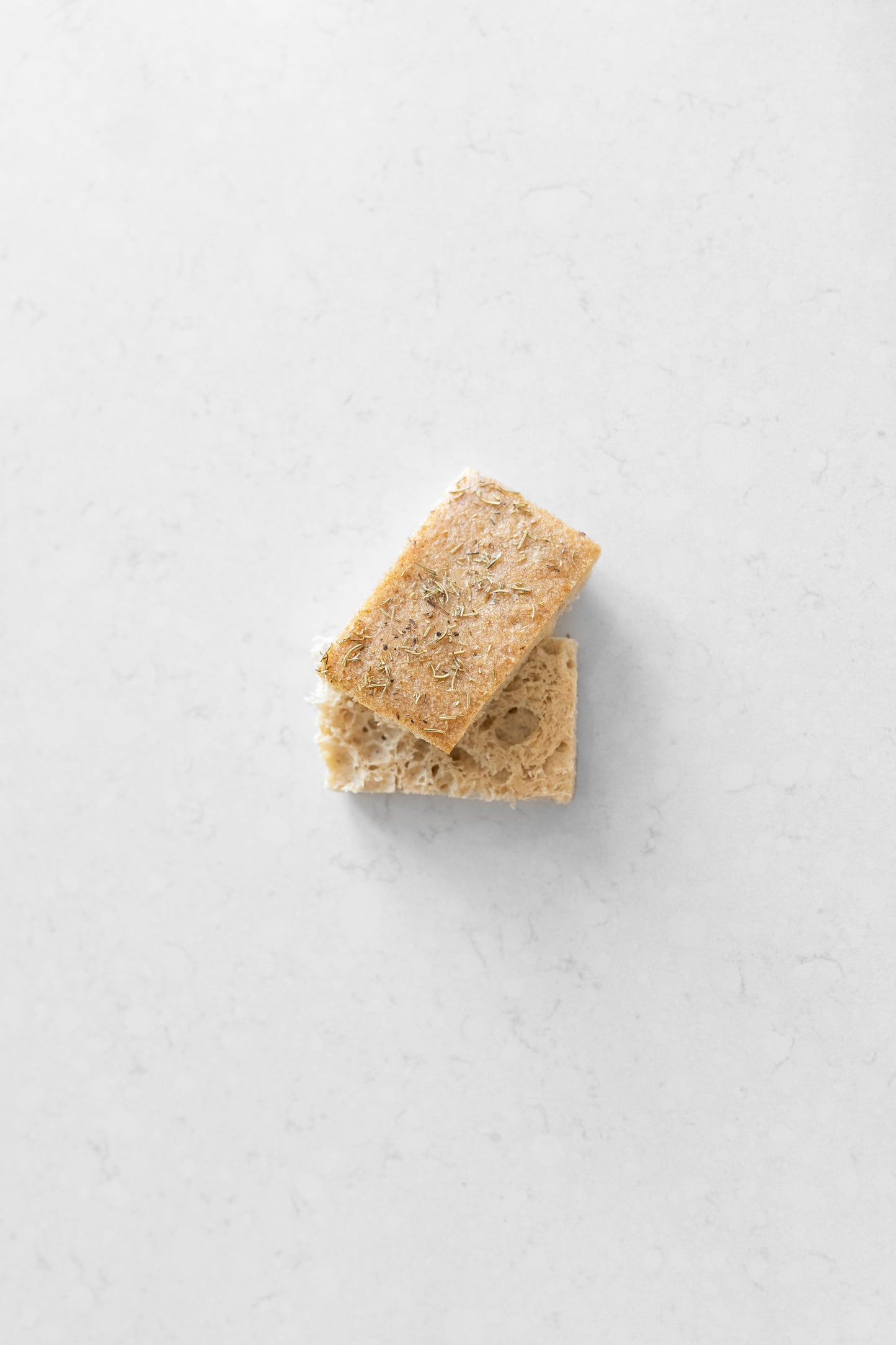 Two slices of gluten-free rosemary focaccia sourdough bread from Heaven Gluten Free Bakery, showing crispy crust and flavorful rosemary topping.