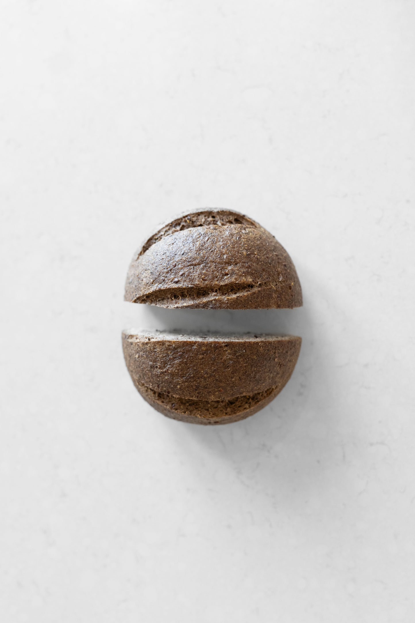 Gluten-free vegan sourdough boule with flaxseed and allspice from Heaven Gluten Free Bakery, shown sliced with a crusty exterior.