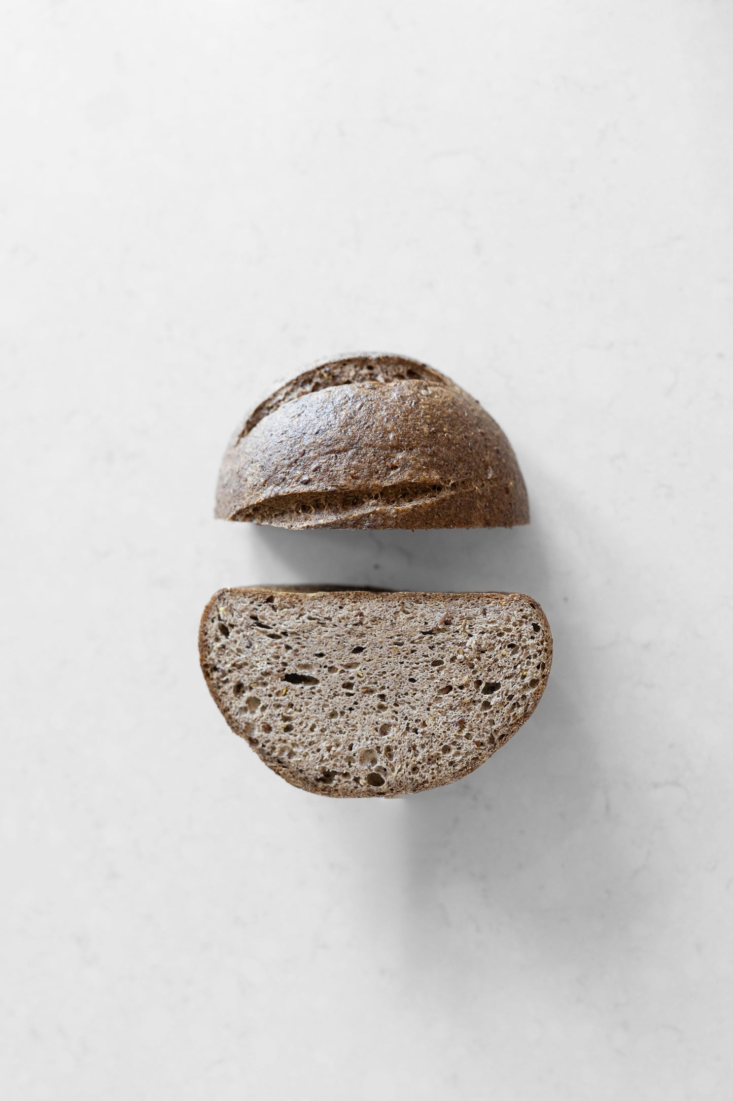 Dark flaxseed-allspice sourdough boule from Heaven Gluten Free Bakery, vegan and gluten-free, with a rustic crust and seeded interior.