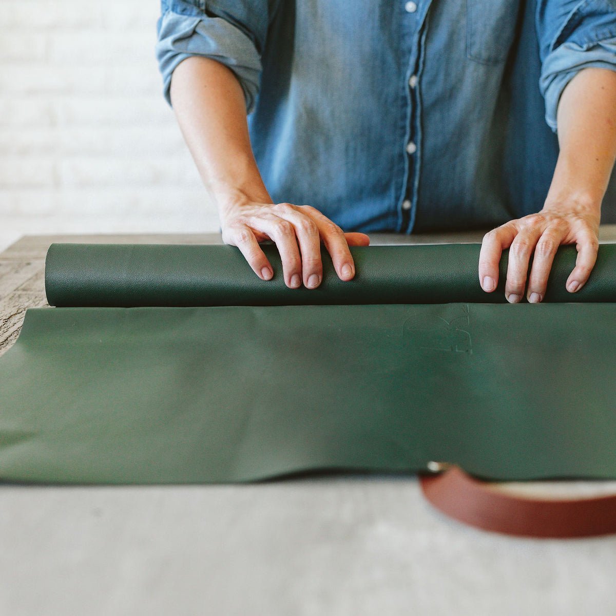Arber repotting mat in green with plant pot and gardening tools on a wooden surface for plant repotting.