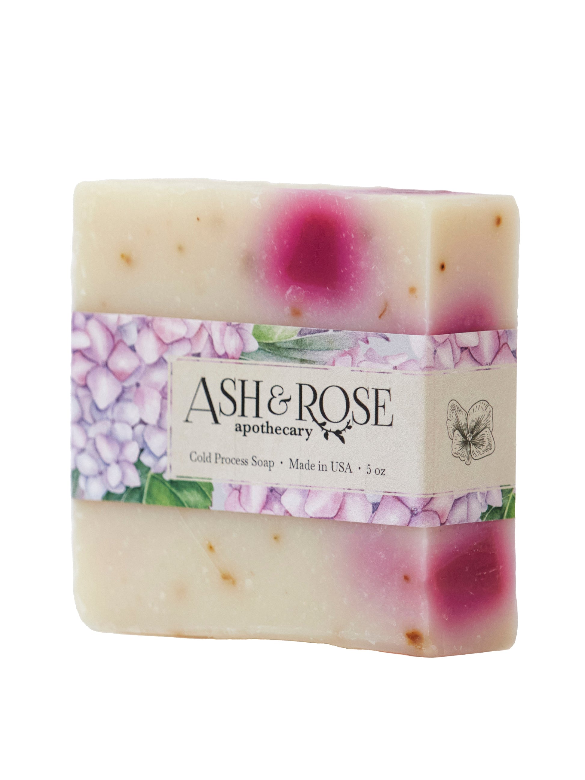The Ash & Rose Pink Hydrangea Soap Scrub Bar is a handmade, natural vegan soap (5 oz) with cream and pink marbling. Wrapped in a floral label with purple flowers and green leaves, this USA-made bar brings luxury to your bath.