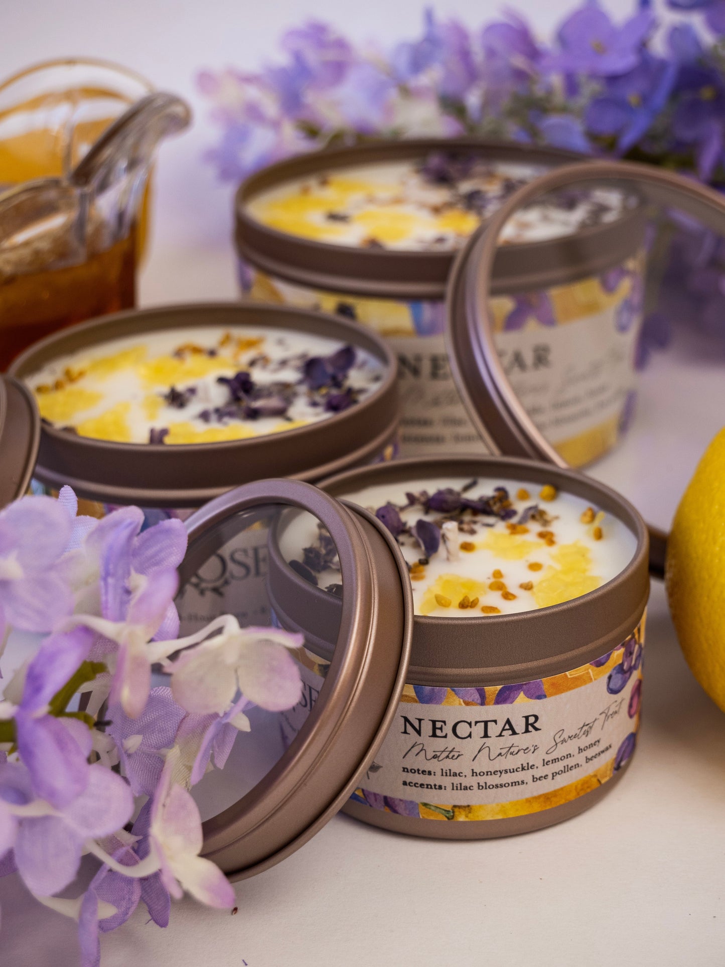 Ash & Rose Nectar Lilac Lemon Honey candle in a 4 oz glass jar, showcasing the candle’s lilac and honey scent with a lit wick.