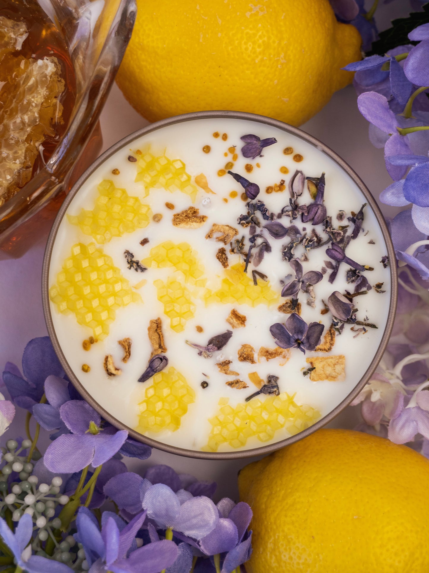 Ash & Rose Nectar Lilac Lemon Honey candle in a 4 oz jar with a purple, yellow, and honey-colored design and a lit wick.