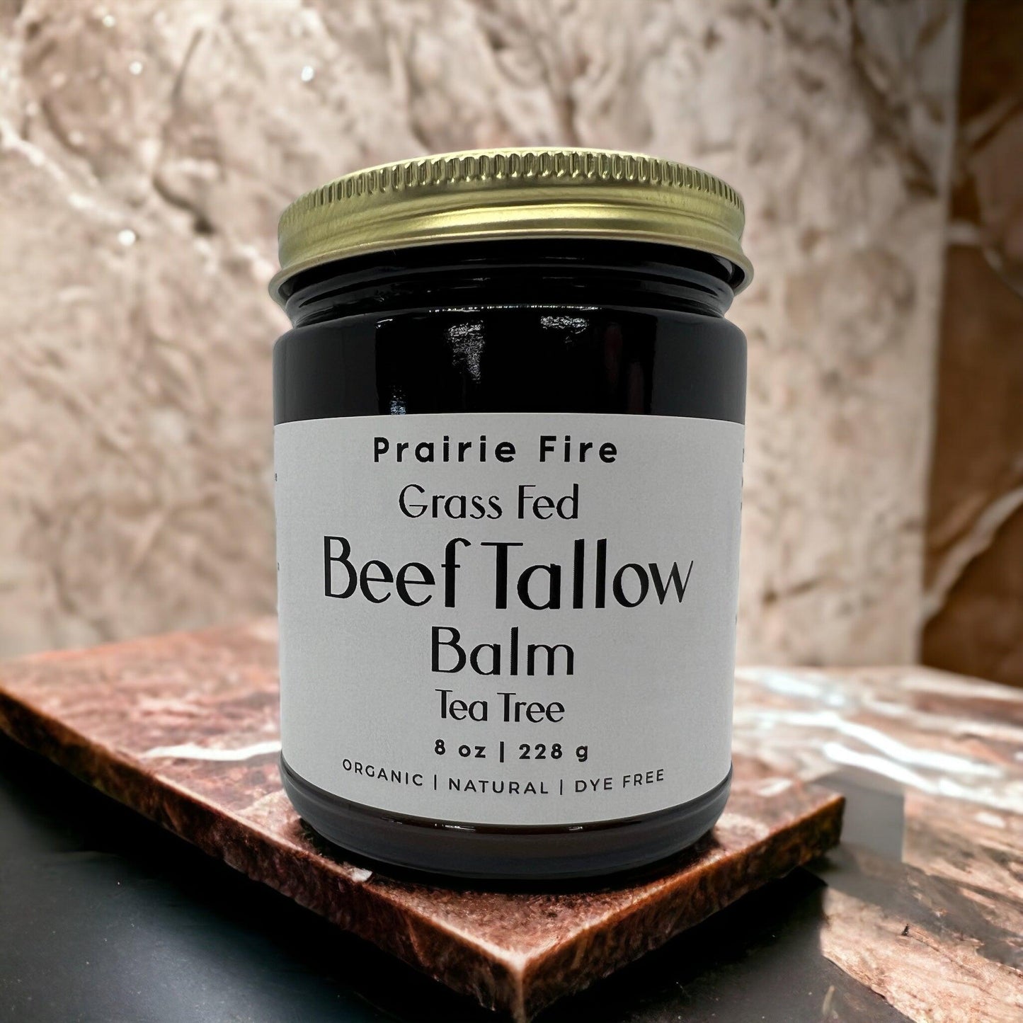 An 8 oz jar of Prairie Fire Tallow, Candles, and Lavender Beef Tallow Balm—organic, grass fed and finished, and made in the USA—rests on a marble surface against a beige backdrop; its a moisturizing natural skin care product.
