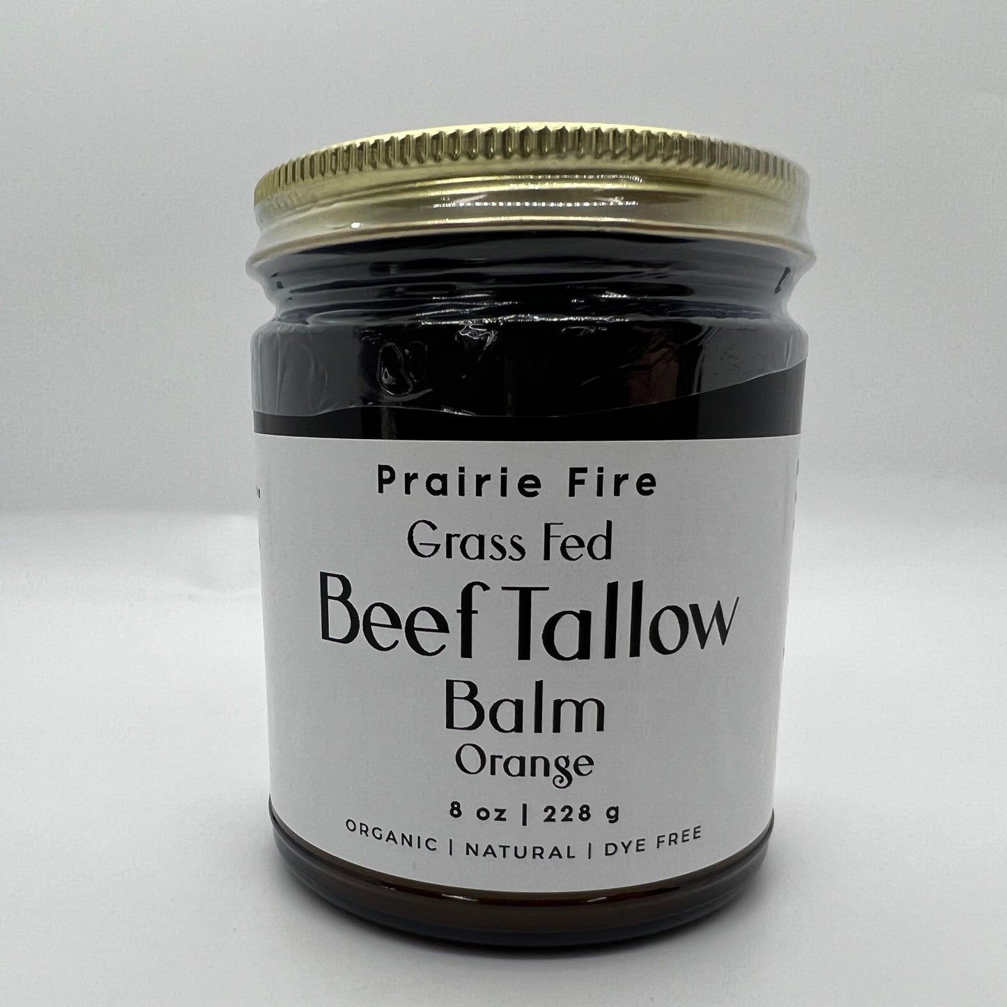 A glass jar with a gold lid labeled Prairie Fire Tallow, Candles, and Lavender Beef Tallow Balm - 8 oz, organic grass-fed and finished, made in the USA—an ideal natural moisturizer for skin care—sits on a white surface.
