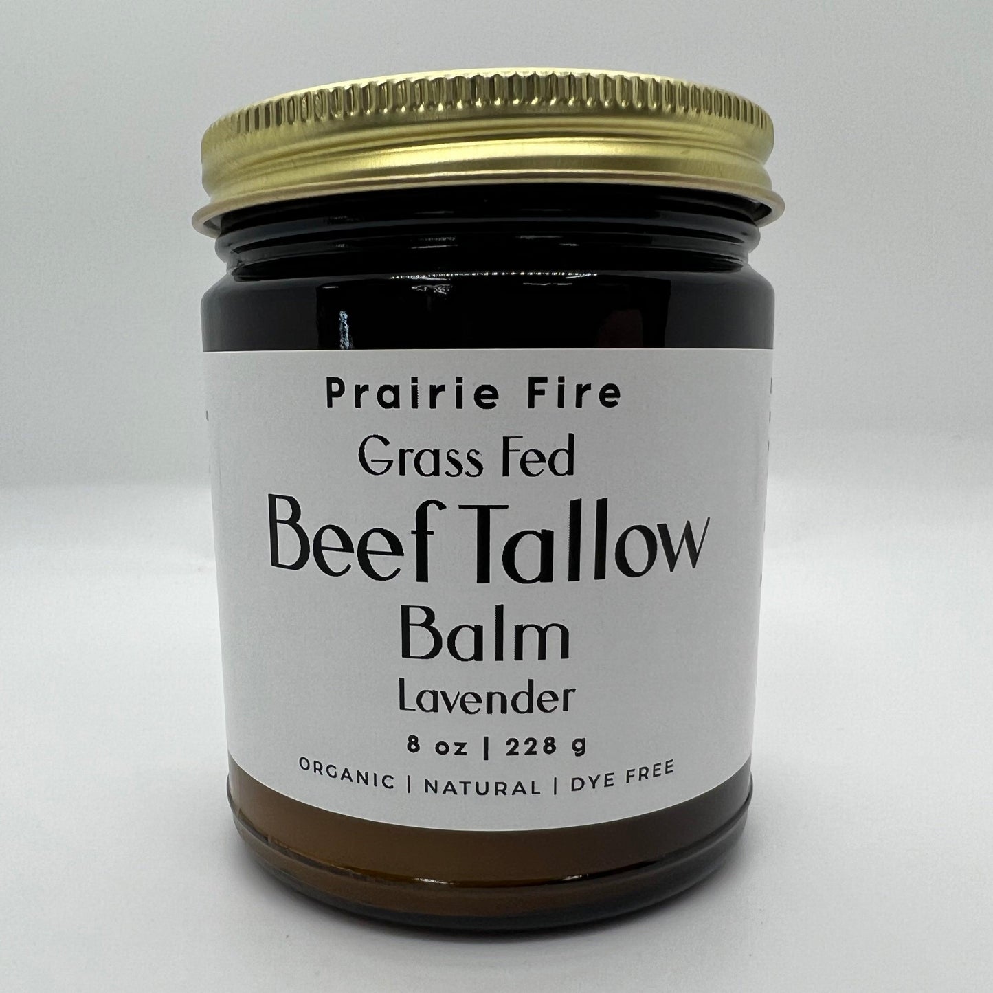 A jar of Prairie Fire Tallow, Candles, and Lavender Beef Tallow Balm (8 oz), made in the USA from organic grass-fed and finished tallow, is a natural, dye-free moisturizer featuring lavender and a gold lid with white label.