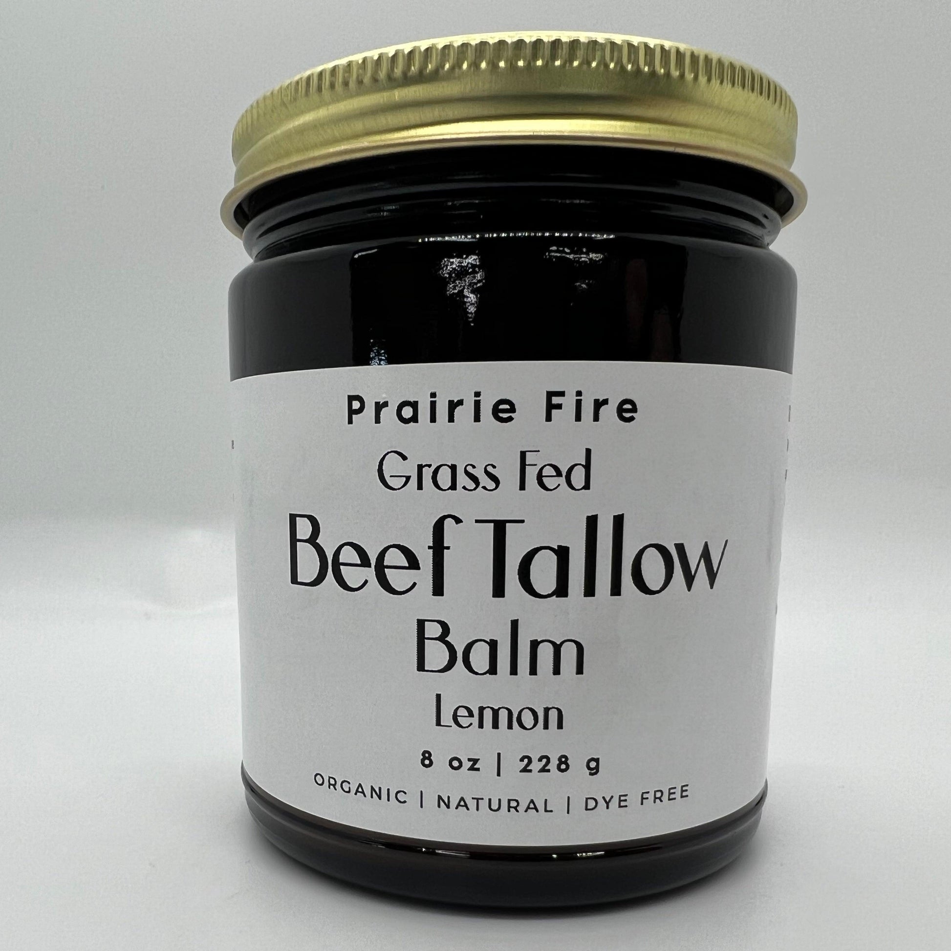 A dark glass jar with a gold lid labeled Prairie Fire Tallow, Candles, and Lavender Beef Tallow Balm - 8 oz - Organic Grass Fed and Finished Moisturizing Skin Care is displayed against a plain white background.