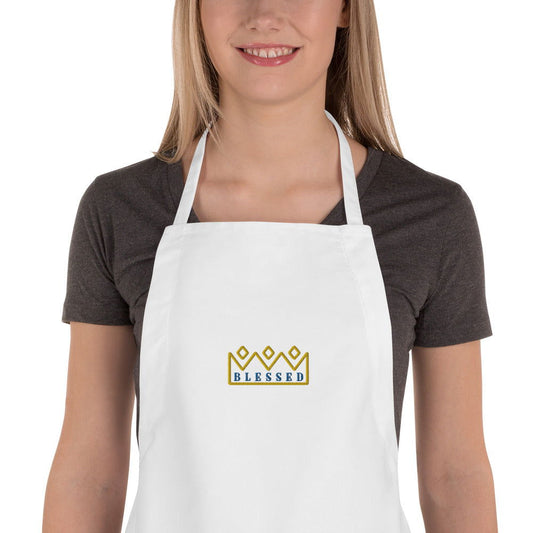 A distorted image shows a person in an Embroidered Apron - Blessed with Crowns ~ Custom Design by Blessings Grow Meadows, featuring an adjustable neck loop and unique glitched patterns, creating a distinctive kitchen accessory look.