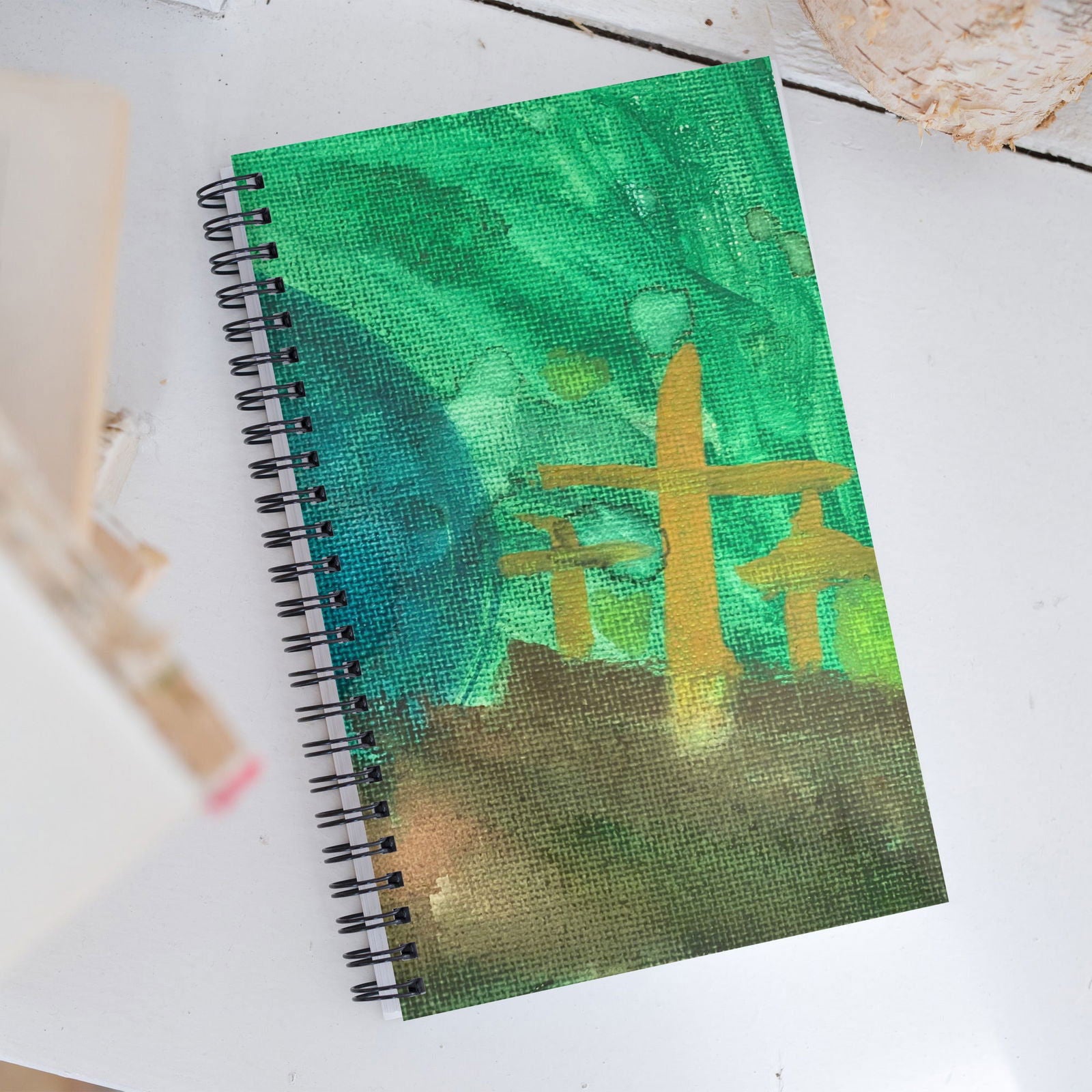 Acrylic painting on a spiral-bound notebook depicting a golden torii gate in a vibrant green landscape with teal and brown accents
