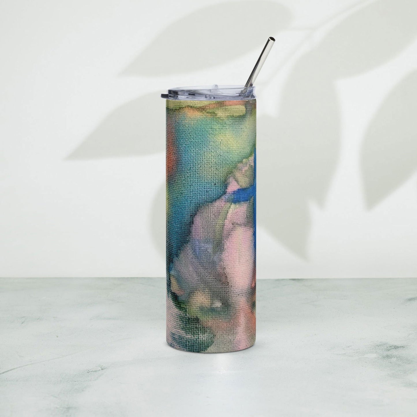 Abstract art tumbler with a stainless steel straw showing teal blue pink and orange watercolor wash on a canvas texture