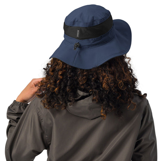 Columbia Sportswear navy blue sun hat with black mesh and drawstring, worn by a model with curly brown and black hair, showcasing the hat's back detail and adjustable features
