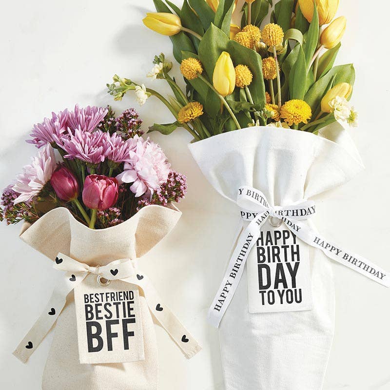 The Blessings Grow Meadows Bouquet Bag - BFF holds two fabric-wrapped bouquets—pink/purple “Best Friend BFF” and yellow “Happy Birthday to You”—in a reusable canvas bag, making it a thoughtful gift for flower lovers.