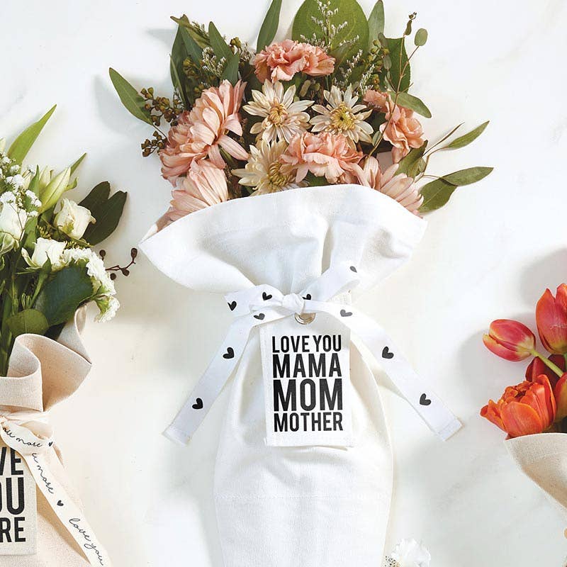 The Bouquet Bag - Mama by Blessings Grow Meadows Merch & More features pink daisies, green leaves, and a ribbon with "LOVE YOU MAMA MOM MOTHER." Two other bouquets are partially visible—an ideal gift for mama.