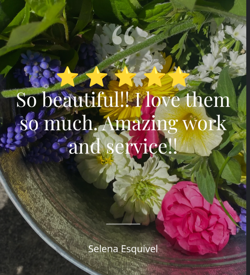Photograph of a vibrant flower arrangement featuring bright pink, yellow, and purple blooms in a rustic metal container.
