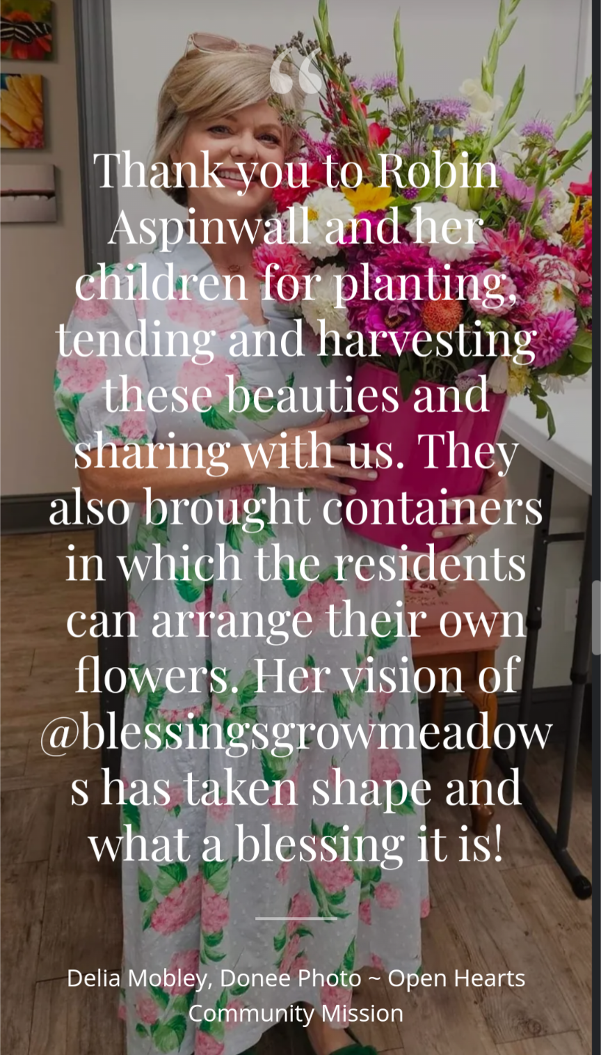Photo by Delia Mobley, a woman in a pink floral dress holds a vibrant bouquet featuring dahlias, zinnias, and gladioli in a pink container.
